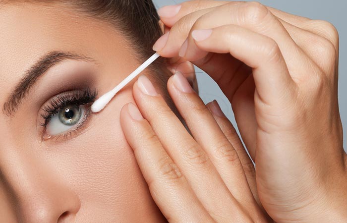 Woman cleaning eyes with cotton bud