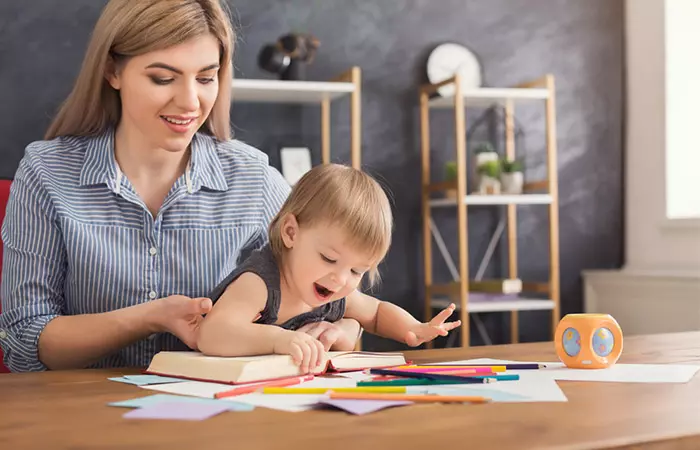 Mother distracting baby from thumb sucking with paintings and book