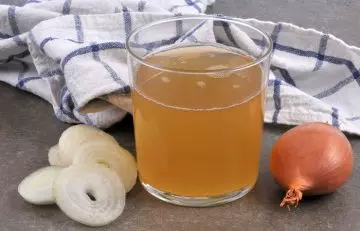 Onion, onion slices and freshly squeezed onion juice in a small glass