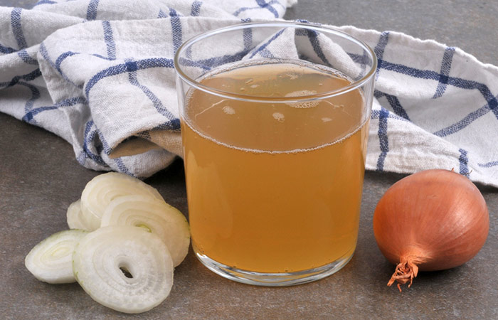 Onion, onion slices and freshly squeezed onion juice in a small glass
