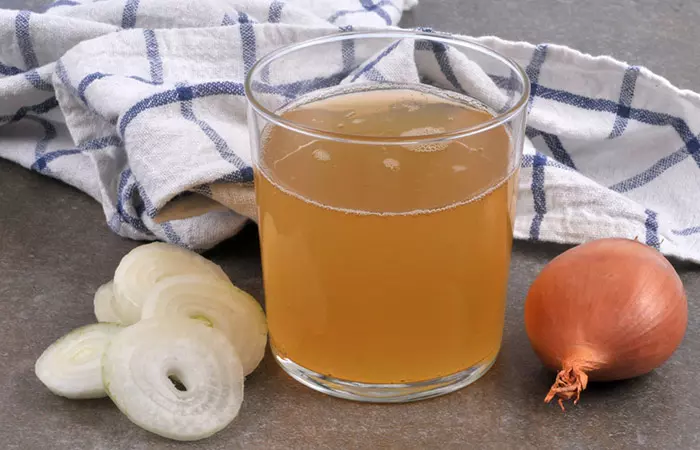 Onion, onion slices and freshly squeezed onion juice in a small glass