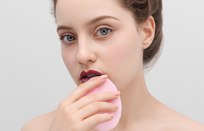 Closeup of a woman applying powder on her lips to prevent lipstick transferring.
