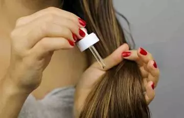 A woman applying oil on dry hair
