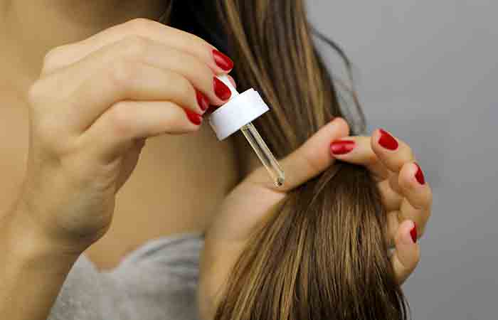A woman applying oil on dry hair
