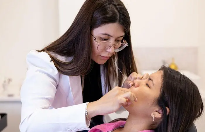 A beautician doing threading to remove facial hair