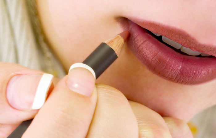 A closeup of a woman applying a lip liner to prevent lipstick transferring.