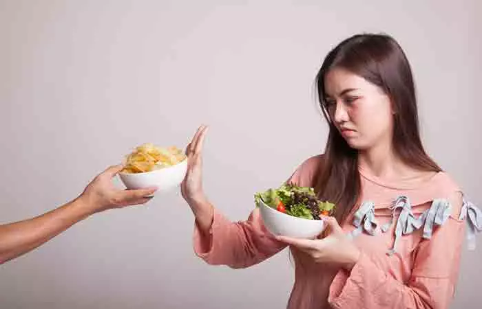 Teen girl picks a healthy salad over fried junk food for weight loss