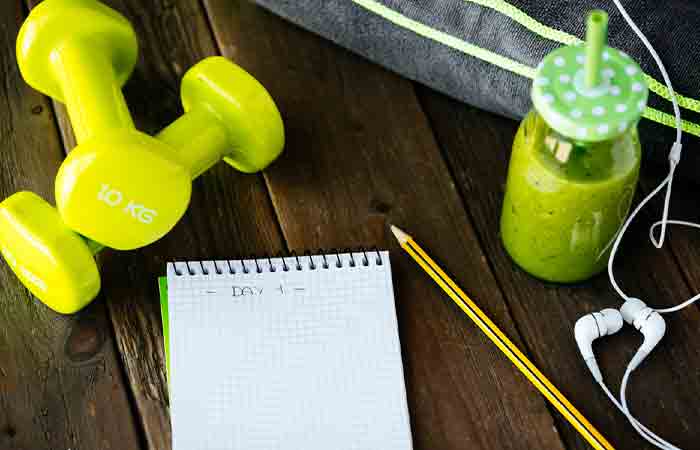 A journal with dumbbells and healthy drinks to document and execute weight loss goals
