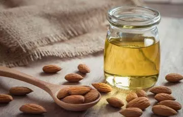 Almond oil in glass bottle with some almonds 