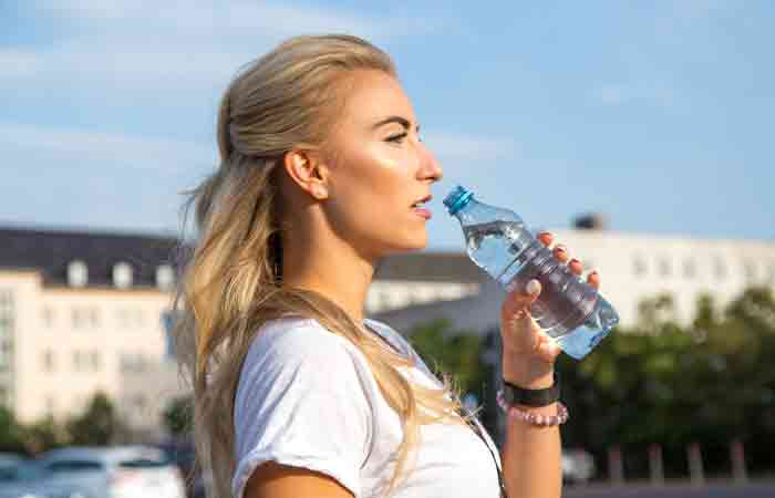 Side view of a woman drinking bottled mineral water