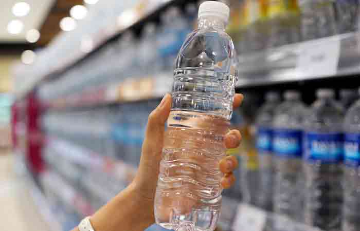 Person holding mineral water in a plastic bottle