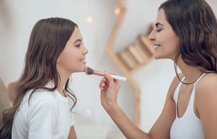 A woman applying makeup on the chin of another woman.