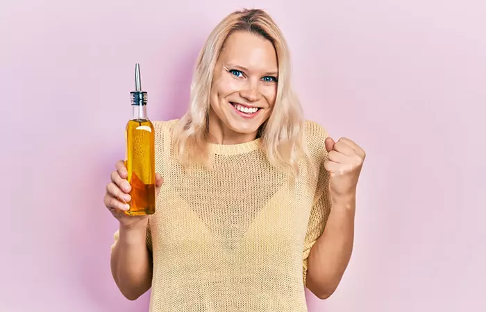 Happy woman holding a bottle of castor oil