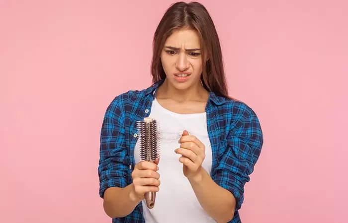 Beautiful woman looking at brush with hair stuck in it