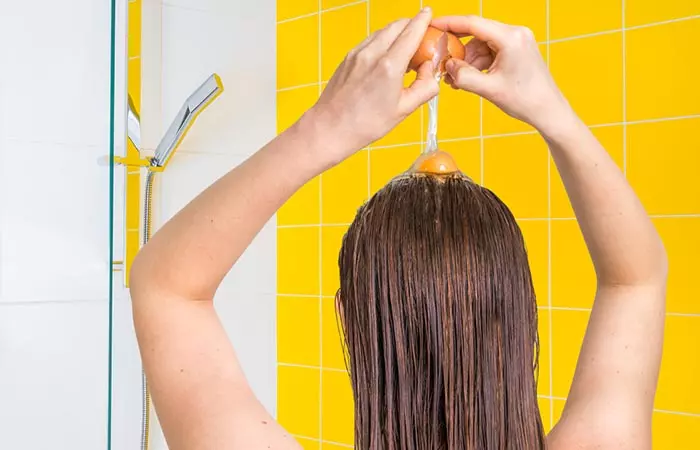 A woman is applying egg yolk to her hair.