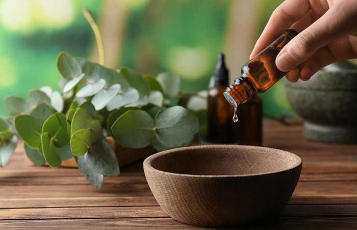 Closeup of woman pouring essential oils in a bowl for muscle weakness
