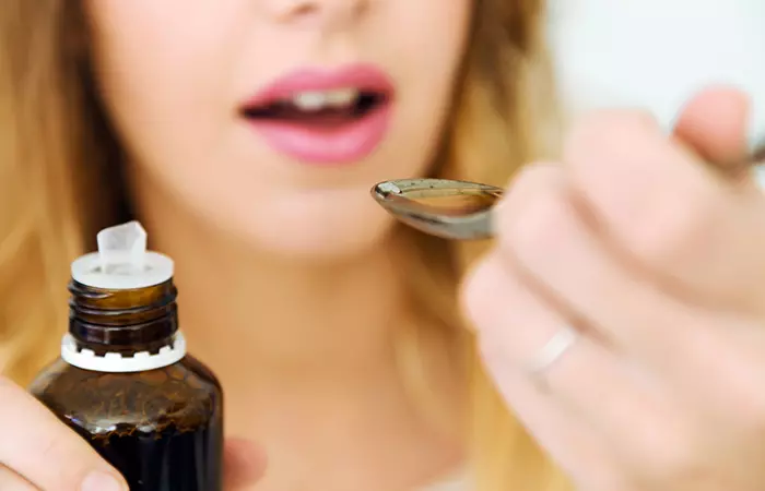 Close up of a woman having a tablespoon of castor oil