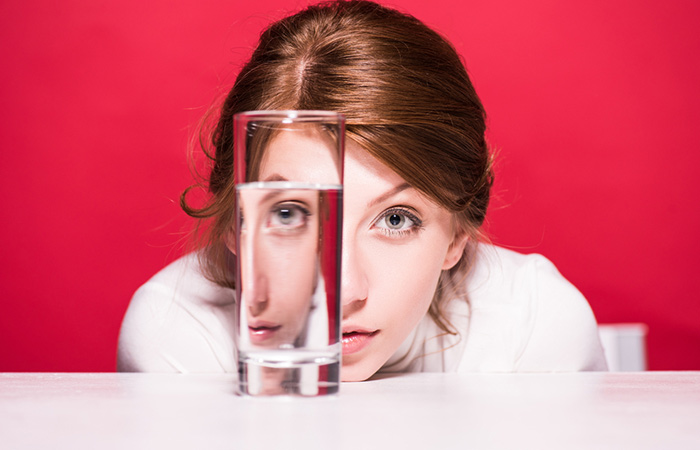Woman thinking how much water to drink by looking at glass