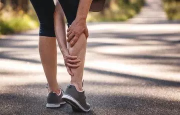 A woman experiencing calf muscle cramp on her jog