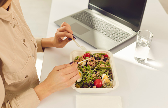 Woman enjoys a low calorie meal with a glass of water at work as part of her weight loss plan