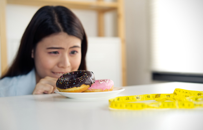 Woman controlling her hunger for donuts