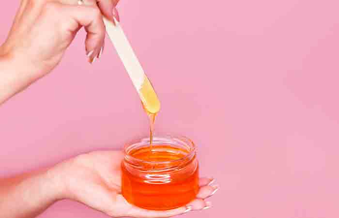 Closeup of a woman's hand holding honey jar to soften the skin