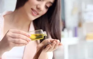 Woman applying castor and tea tree oil on hair