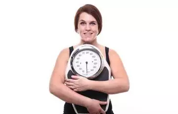 Woman with a weighing scale happy that is managing her weight
