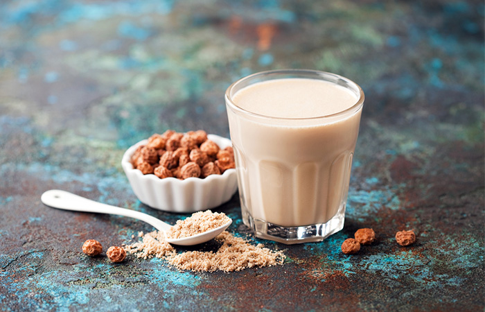 A glass of tiger nut milk with a spoon full of tiger nut powder
