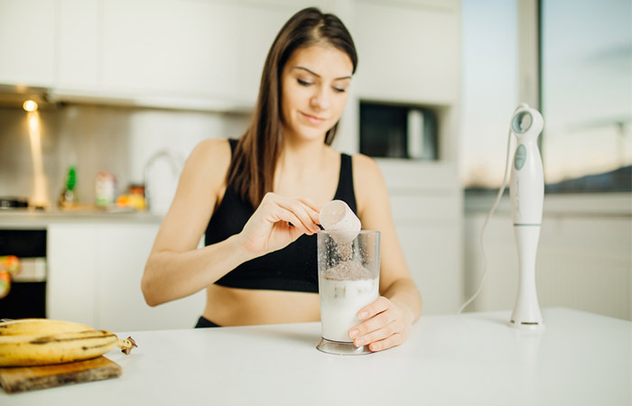 Woman adding a scoop of whey protein to her milk