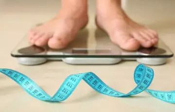 Closeup of woman standing on weighing scales and lost weight due to regular evening walks 