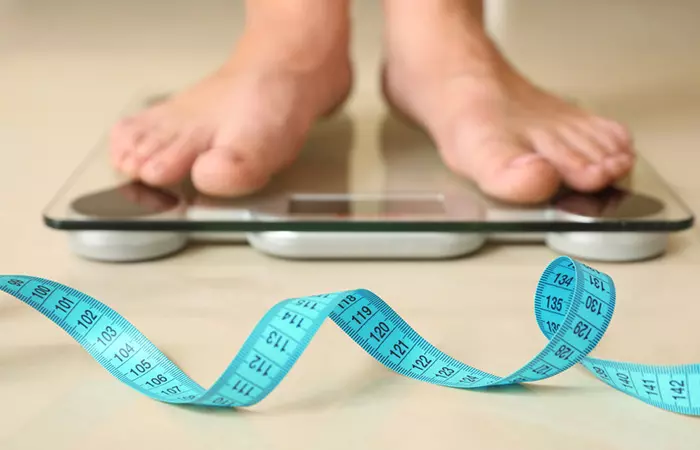 Closeup of woman standing on weighing scales and lost weight due to regular evening walks 