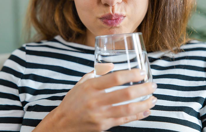 Woman gargling with a glass of water and hydrogen peroxide