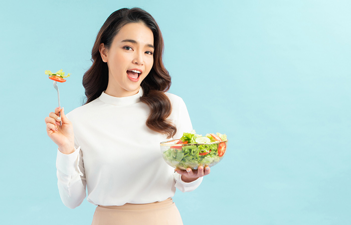 A happy woman eating a delicious salad