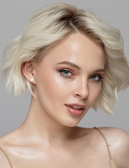 Uneven platinum curls with side bangs make a bold and elegant asymmetrical bob hairstyle