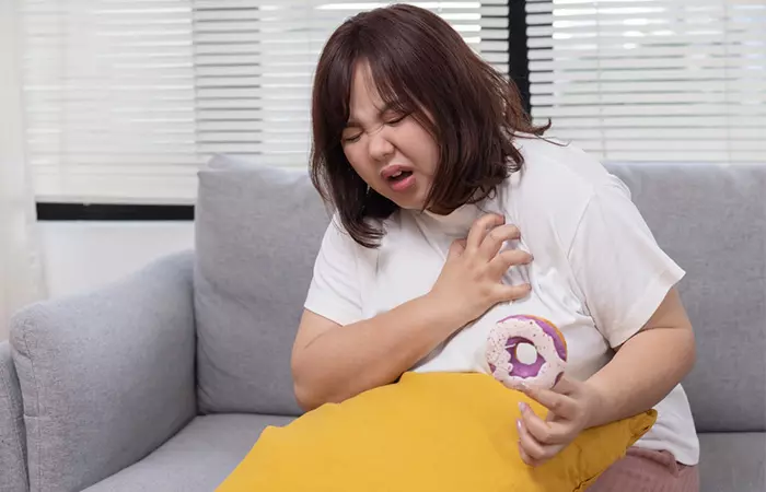 Woman holding her chest due to poor breakfast diet