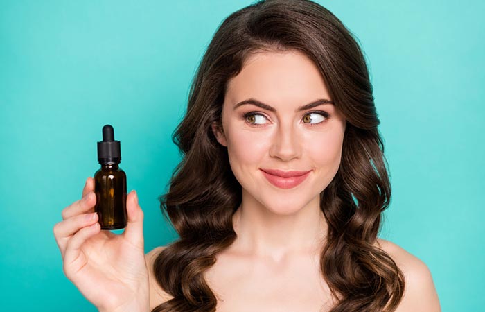 Woman with good skin and hair health holding essential oil