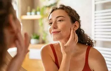Woman checking skin health in the mirror