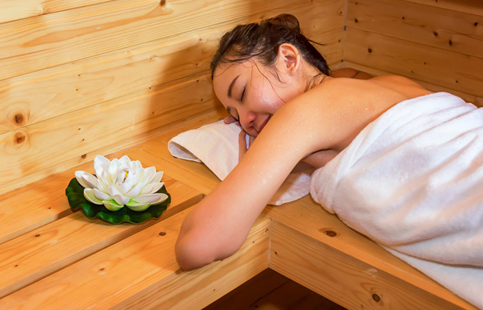 Woman enjoying a relaxing session in the sauna laying on her stomach