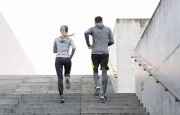 Couple run up the stairs during their morning cardio circuit to burn calories