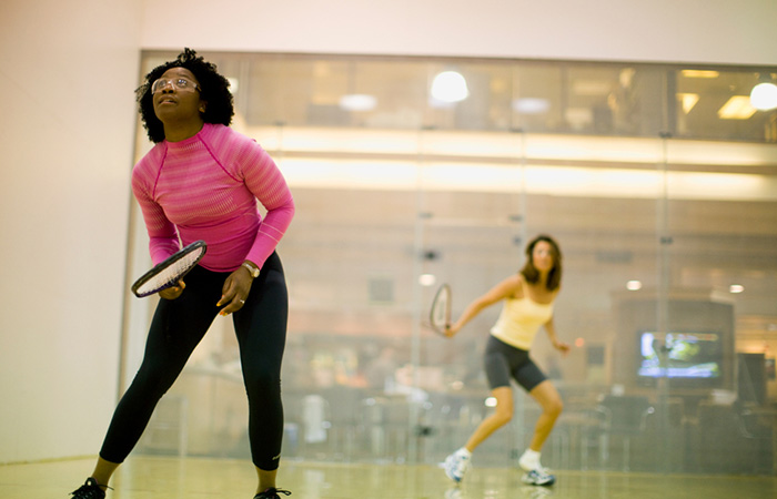 Two women engaged in a session of racquetball to burn calories