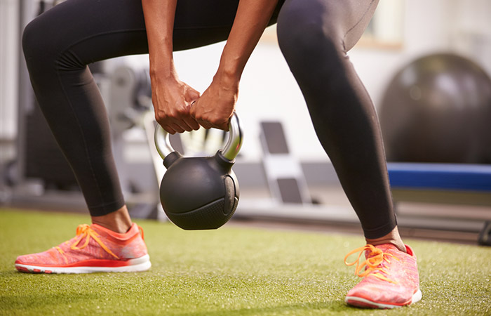 Lower body shot of woman training with a kettle bell to burn calories