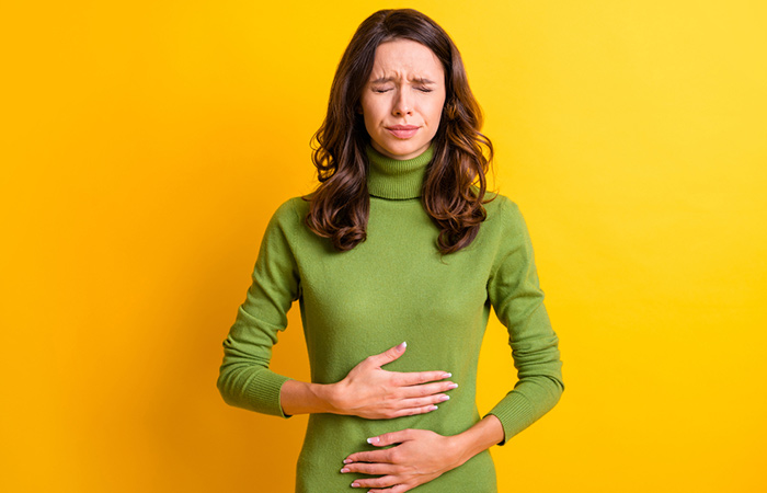 Woman experiencing upset stomach as a side effect of chasteberry