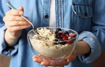 Woman eating porridge with antioxidant-rich berries
