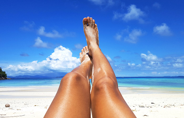 Legs of a woman sunbathing on the beach after having oiled herself