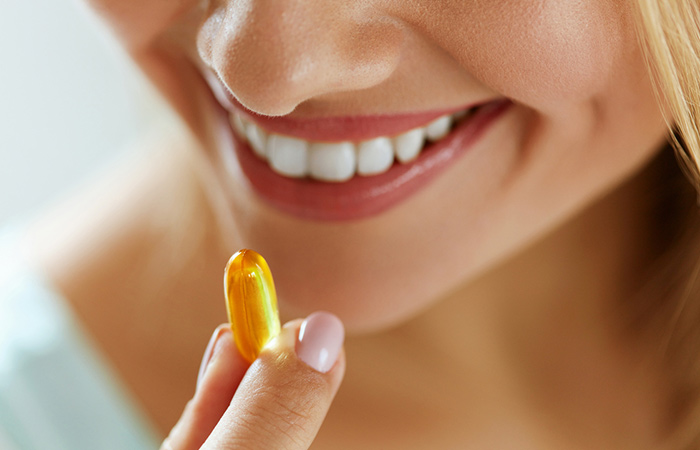 Woman taking fish oil supplement for its health benefits