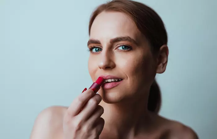 Woman applying light pink color on lips for baby lips look 