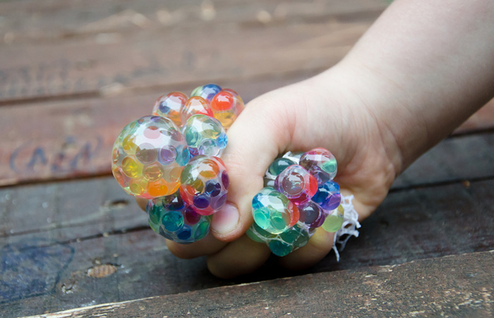 A child’s hand squishing a mesh stress ball