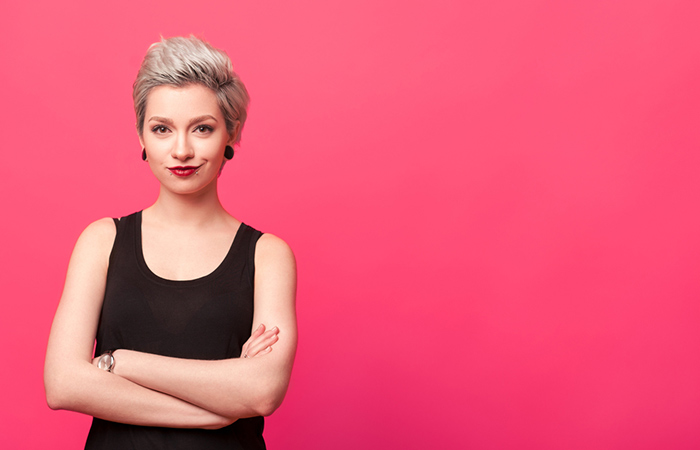Confident woman standing with arms crossed isolated over pink background