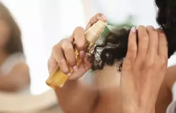 Woman spraying lemon juice hair spray on dark hair